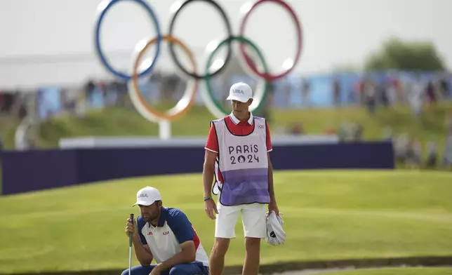 Scottie Scheffler, of the United States, looks at his putt on the 18th green during the final round of the men's golf at the 2024 Summer Olympics, Sunday, Aug. 4, 2024, at Le Golf National in Saint-Quentin-en-Yvelines, France. (AP Photo/Matt York)