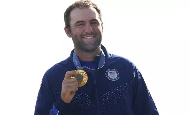 Gold medalist Scottie Scheffler, of the United States, poses with his medal following the medal ceremony for men's golf during the medal ceremony at the 2024 Summer Olympics, Sunday, Aug. 4, 2024, at Le Golf National in Saint-Quentin-en-Yvelines, France. Scottie Scheffler, of the United States, won the gold medal with Tommy Fleetwood, of Britain, silver and Hideki Matsuyama, of Japan, the bronze.(AP Photo/Matt York)