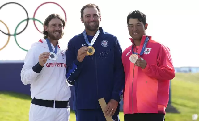 Gold medalist Scottie Scheffler, of the United States, centre, with Tommy Fleetwood, of Britain, silver medal, and Hideki Matsuyama, of Japan, with the bronze medal pose for the media following the medal ceremony for men's golf at the 2024 Summer Olympics, Sunday, Aug. 4, 2024, at Le Golf National in Saint-Quentin-en-Yvelines, France. (AP Photo/Matt York)