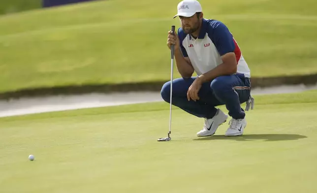 Scottie Scheffler, of the United States, looks at the lie of his putt on the 18th green during the final round of the men's golf at the 2024 Summer Olympics, Sunday, Aug. 4, 2024, at Le Golf National in Saint-Quentin-en-Yvelines, France. (AP Photo/Matt York)