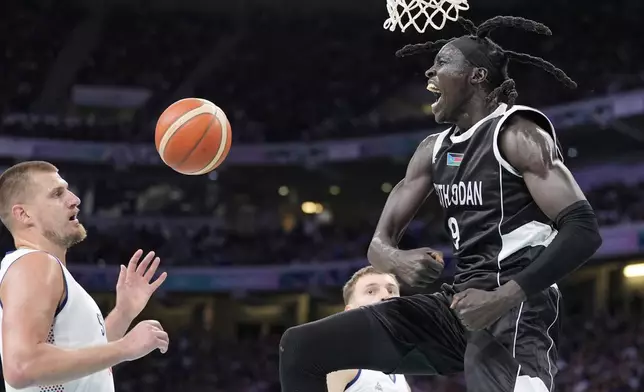 South Sudan's Wenyen Gabriel, right, celebrates after dunking as Serbia's Nikola Jokic watches during a men's basketball game at the 2024 Summer Olympics, Saturday, Aug. 3, 2024, in Villeneuve-d'Ascq, France. (AP Photo/Michael Conroy)