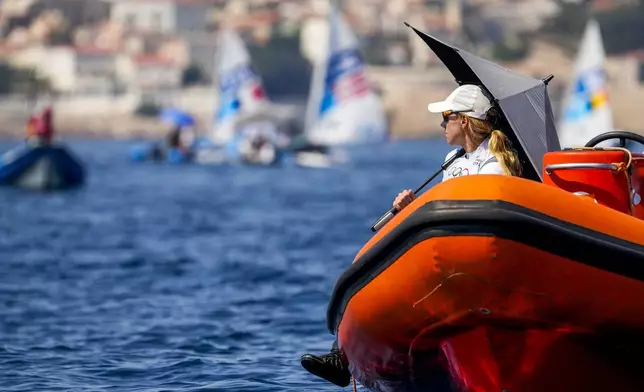 Marit Bouwmeester of the Netherlands shelters against the sun with an umbrella as she waits with others for the start of the ILCA 6 dinghy class final race during the 2024 Summer Olympics, Tuesday, Aug. 6, 2024, in Marseille, France. (AP Photo/Jacquelyn Martin)