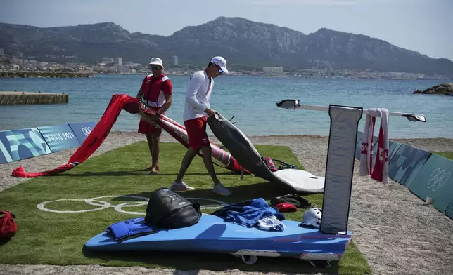 Poland athletes pack up a windsurf board after the men's windsurfing medal race was postponed until Saturday due to lack of wind during the 2024 Summer Olympics, Friday, Aug. 2, 2024, in Marseille, France. (AP Photo/Daniel Cole)