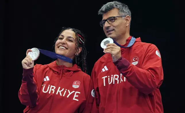 Turkey's Savval Ilayda Tarhan, left, and Yususf Dikec pose for a photograph after winning the silver medal in the 10m air pistol mixed team event at the 2024 Summer Olympics, Tuesday, July 30, 2024, in Chateauroux, France. (AP Photo/Manish Swarup)