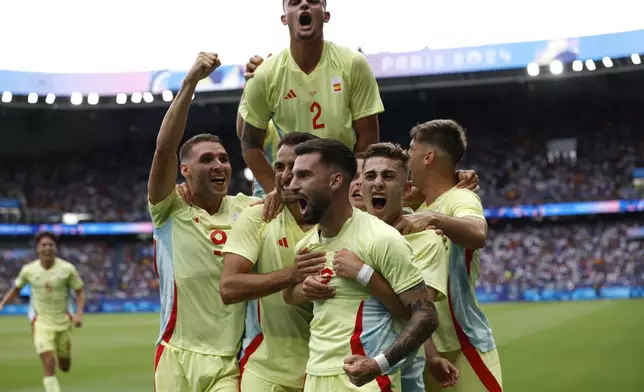 Spain's Baena Alex, center, celebrates with his teammates after scoring his goal during the men's soccer gold medal match between France and Spain at the Parc des Princes during the 2024 Summer Olympics, Friday, Aug. 9, 2024, in Paris, France. (AP Photo/Aurelien Morissard)