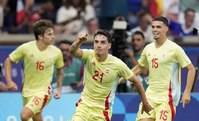 Spain's Sergio Camello, centre, celebrates after scoring his team's fourth goal during the men's soccer gold medal match between France and Spain at the Parc des Princes during the 2024 Summer Olympics, Friday, Aug. 9, 2024, in Paris, France. (AP Photo/Francisco Seco)