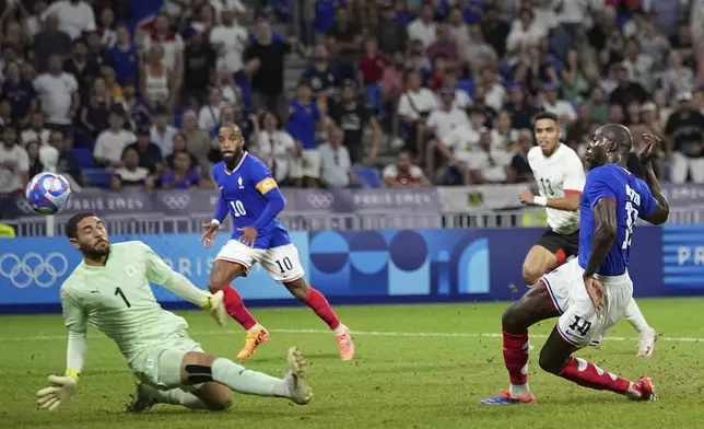 France's Jean-Philippe Mateta, right, scores his side's first goal past Egypt's goalkeeper Hamza Alaa during the men's semifinal soccer match between France and Egypt, at Lyon Stadium, during the 2024 Summer Olympics, Monday, Aug. 5, 2024, in Decines, France. (AP Photo/Laurent Cipriani)