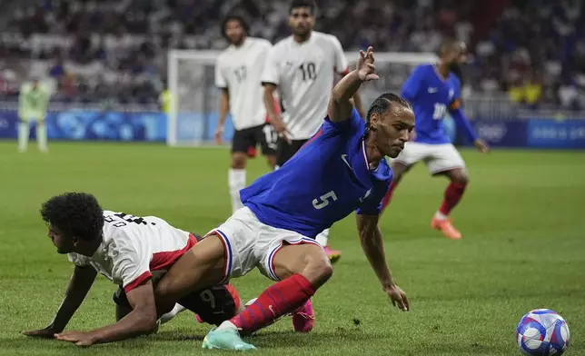 France's Kiliann Sildillia, right, is fouled by Egypt's Osama Faisal during the men's semifinal soccer match between France and Egypt, at Lyon Stadium, during the 2024 Summer Olympics, Monday, Aug. 5, 2024, in Decines, France. (AP Photo/Laurent Cipriani)