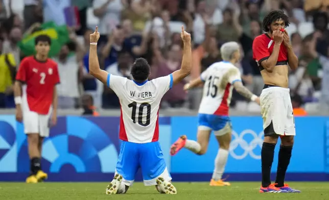 Paraguay's Wilder Viera (10) and Egypt's Mohamed Elneny, right, react after Paraguay's Diego Gomez, not visible, scored a goal during a men's quarterfinal soccer match between Egypt and Paraguay at the 2024 Summer Olympics, Friday, Aug. 2, 2024, at Marseille Stadium in Marseille, France. (AP Photo/Julio Cortez)