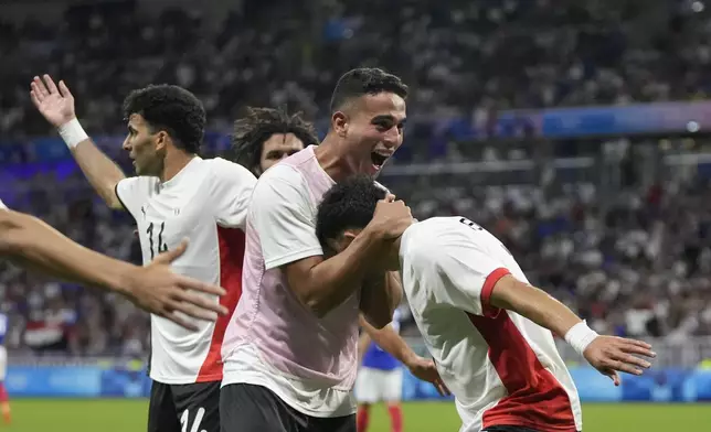 Egypt's Mahmoud Saber, right, is congratulated by teammates after scoring his side's opening goal during the men's semifinal soccer match between France and Egypt, at Lyon Stadium, during the 2024 Summer Olympics, Monday, Aug. 5, 2024, in Decines, France. (AP Photo/Silvia Izquierdo)