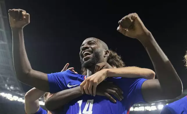 France's Jean-Philippe Mateta celebrates with teammates after scoring his side's 2nd goal in extra time during the men's semifinal soccer match between France and Egypt, at Lyon Stadium, during the 2024 Summer Olympics, Monday, Aug. 5, 2024, in Decines, France. (AP Photo/Silvia Izquierdo)