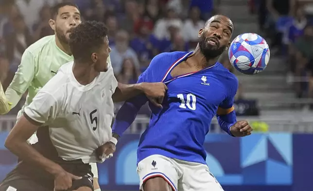 Egypt's Hossam Abdelmaguid, left, pulls on the jersey of France's Alexandre Lacazette during the men's semifinal soccer match between France and Egypt, at Lyon Stadium, during the 2024 Summer Olympics, Monday, Aug. 5, 2024, in Decines, France. (AP Photo/Laurent Cipriani)