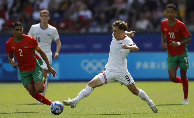 Morocco's Achraf Hakimi, left, challenges Griffin Yow of the United States during the quarterfinal men's soccer match between Morocco and the United States at the Parc des Princes during the 2024 Summer Olympics, Friday, Aug. 2, 2024, in Paris, France. (AP Photo/Aurelien Morissard)