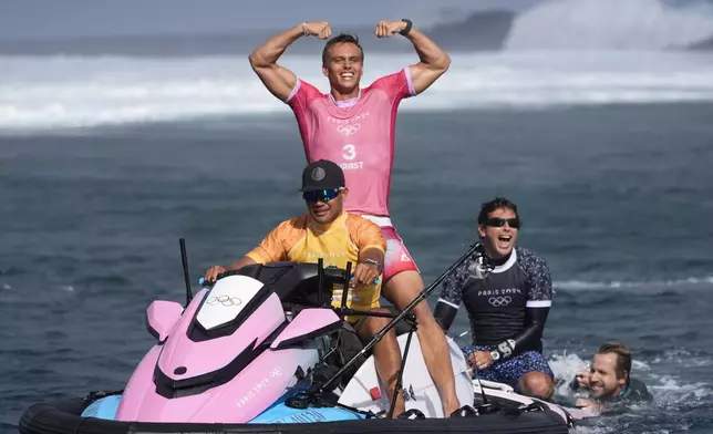 Kauli Vaast, of France, center, celebrates alongside his coach Jeremy Flores, second from right, after winning the gold medal match of the surfing competition at the 2024 Summer Olympics, Monday, Aug. 5, 2024, in Teahupo'o, Tahiti. (AP Photo/Gregory Bull)