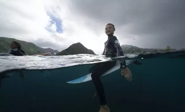 Tauirai Henriou Oopa, 10, right, waits for a wave alongside Kiara Goold, 14, at their home shore break during a break in the 2024 Summer Olympics surfing competition, Wednesday, July 31, 2024, in Teahupo'o, Tahiti. While Teahupo'o has been a coveted destination for surfers from around the world for decades, it's only in more recent years that local surf culture and talent has begun to develop across Tahiti. (AP Photo/Gregory Bull)