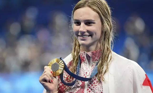 Summer McIntosh, of Canada, celebrates with the gold medal during the awards ceremony for the women's 200-meter butterfly at the 2024 Summer Olympics in Nanterre, France, Thursday, Aug. 1, 2024. (AP Photo/Martin Meissner)