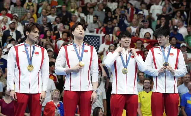 China's Xu Jiayu, Qin Haiyang, Sun Jiajun, and Pan Zhanle pose for a photo with their gold medals on the podium for the men's 4x100-meter medley relay at the Summer Olympics in Nanterre, France, Sunday, Aug. 4, 2024. (AP Photo/Natacha Pisarenko)