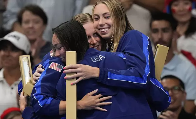 United States' gold medal winners Lilly King, Gretchen Walsha nd Torri Huske embrace on the podium during the awards ceremony for the women's 4x100-meter medley relay at the Summer Olympics in Nanterre, France, Sunday, Aug. 4, 2024. (AP Photo/Brynn Anderson)