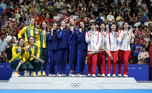 United States' gold medalists pose for a photo on the podium with Australia's silver medalists and China's bronze medalists during the awards ceremony for the women's 4x100-meter medley relay at the Summer Olympics in Nanterre, France, Sunday, Aug. 4, 2024. (AP Photo/Natacha Pisarenko)