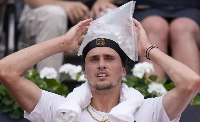 Alexander Zverev of Germany cools his head with ice during a break as he plays against Lorenzo Musetti of Italy during their men's singles quarterfinals match, at the 2024 Summer Olympics, Thursday, Aug.1, 2024, at the Roland Garros stadium in Paris, France. (AP Photo/Andy Wong)