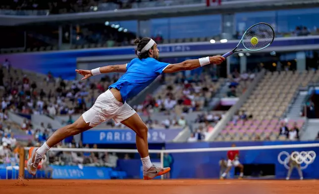 Lorenzo Musetti of Italy returns the ball against Felix Auger-Aliassime of Canada during men's singles bronze medal tennis match at the Roland Garros stadium, at the 2024 Summer Olympics, Saturday, Aug. 3, 2024, in Paris, France. (AP Photo/Manu Fernandez)