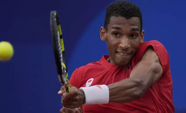 Felix Auger-Aliassime of Canada returns a backhand shot to Casper Ruud of Norway during their men's singles quarterfinals tennis match, at the 2024 Summer Olympics, Thursday, Aug.1, 2024, at the Roland Garros stadium in Paris, France. (AP Photo/Andy Wong)