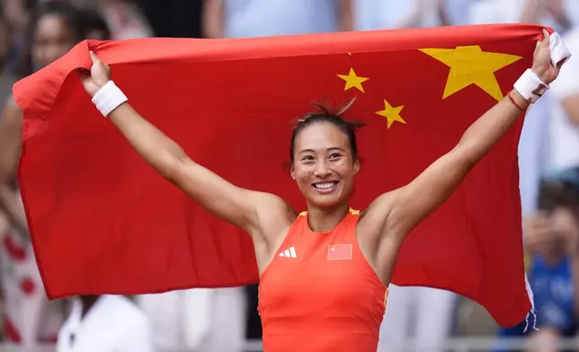 China's Zheng Qinwen holds her national flag after defeating Croatia's Donna Vekic during the Women's Singles tennis final at the Roland Garros stadium at the 2024 Summer Olympics, Saturday, Aug. 3, 2024, in Paris, France. (AP Photo/Manu Fernandez)