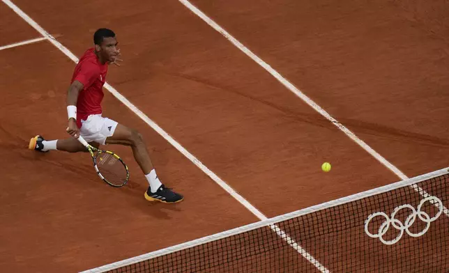 Felix Auger-Aliassime of Canada returns a shot to Lorenzo Musetti of Italy during their men's singles bronze medal match, at the 2024 Summer Olympics, Saturday, Aug. 3, 2024, at the Roland Garros stadium in Paris, France. (AP Photo/Andy Wong)