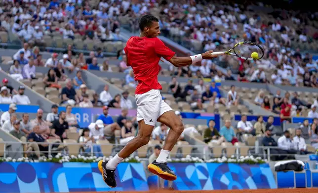 Felix Auger-Aliassime of Canada returns the ball against Lorenzo Musetti of Italy during men's singles bronze medal tennis match at the Roland Garros stadium, at the 2024 Summer Olympics, Saturday, Aug. 3, 2024, in Paris, France. (AP Photo/Manu Fernandez)