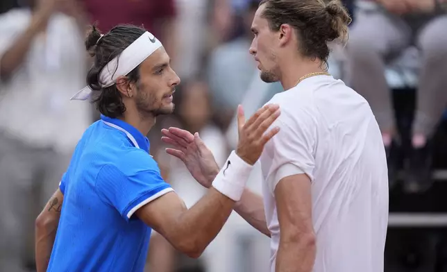 Lorenzo Musetti of Italy is greeted by Alexander Zverev of Germany after winning in their men's singles quarterfinals match, at the 2024 Summer Olympics, Thursday, Aug.1, 2024, at the Roland Garros stadium in Paris, France. (AP Photo/Andy Wong)