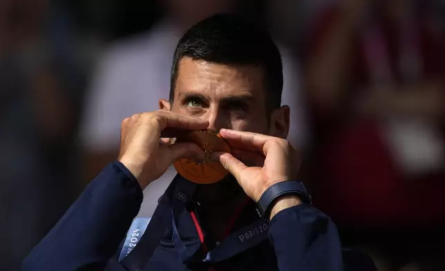 Serbia's Novak Djokovic kisses his gold medal after defeating Spain's Carlos Alcaraz during the men's singles tennis final at the Roland Garros stadium during the 2024 Summer Olympics, Sunday, Aug. 4, 2024, in Paris, France. Djokovic has won his first Olympic gold medal by beating Alcaraz 7-6 (3), 7-6 (2) in the 2024 Games men's tennis singles final. (AP Photo/Louise Delmotte)