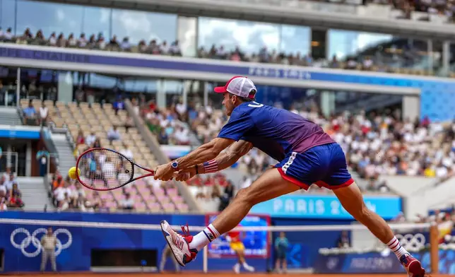 Tommy Paul, of United States returns the ball against Carlos Alcaraz of Spain during their men's quarter-final match at the Roland Garros stadium, at the 2024 Summer Olympics, Thursday, Aug. 1, 2024, in Paris, France. (AP Photo/Manu Fernandez)