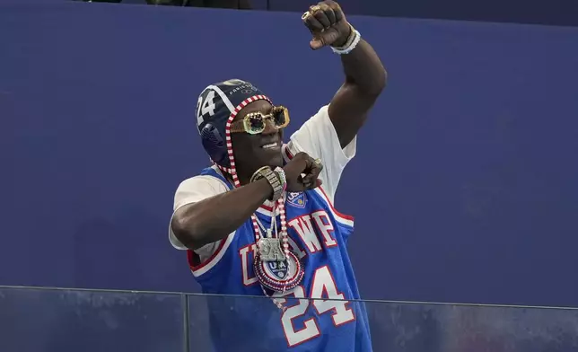 Flavor Flav gestures prior to a women's water polo group B preliminary match between Italy and USA, at the 2024 Summer Olympics, Wednesday, July 31, 2024, in Saint-Denis, France. (AP Photo/Luca Bruno)