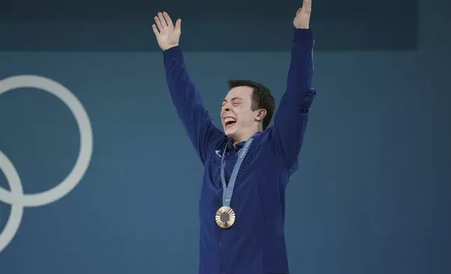 Bronze medalist Hampton Morris of the United States celebrates on the podium during the medal ceremony for the men's 61kg weightlifting event at the 2024 Summer Olympics, Wednesday, Aug. 7, 2024, in Paris, France. (AP Photo/Kin Cheung)