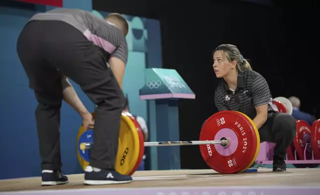 Loaders set the weight on the bar during the women's 59kg weightlifting event at the 2024 Summer Olympics, Thursday, Aug. 8, 2024, in Paris, France. (AP Photo/Kin Cheung)