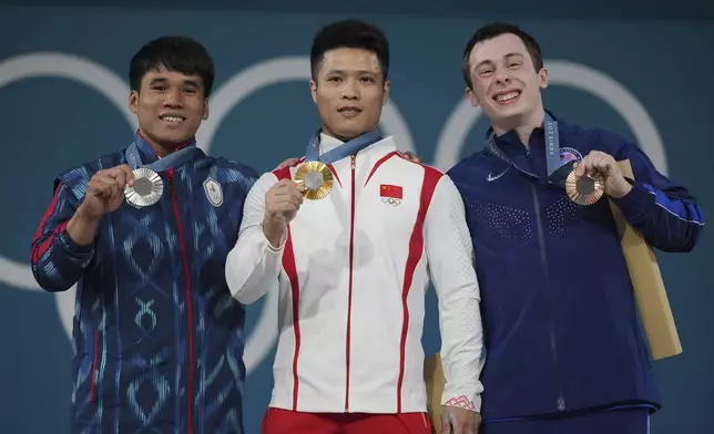 Medalist, from left to right, Theerapong Silachai of Thailand, silver, Li Fabin of China, gold, and Hampton Morris of the United States, bronze, celebrate on the podium during the medal ceremony for the men's 61kg weightlifting event at the 2024 Summer Olympics, Wednesday, Aug. 7, 2024, in Paris, France. (AP Photo/Kin Cheung)