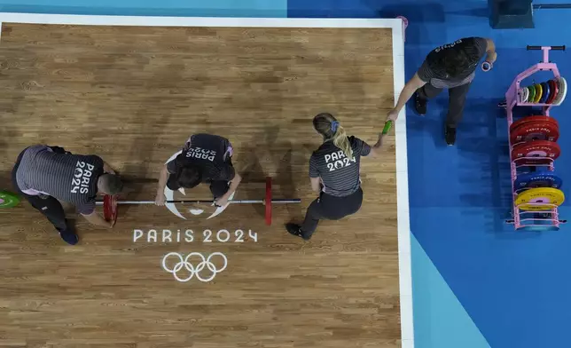 Loaders set the weight on the bar, during the women's 59kg weightlifting event, at the 2024 Summer Olympics, Thursday, Aug. 8, 2024, in Paris, France. (AP Photo/Dita Alangkara,Pool)