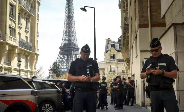 Police officers gather in a street near the Eiffel Tower on the eve of the Paralympic Games opening ceremony, Tuesday, Aug. 27, 2024 in Paris. (AP Photo/Thomas Padilla)