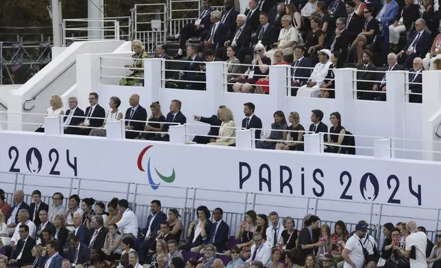 French President Emmanuel Macron points towards the stage as he sits next to his wife Brigitte while they watch the Opening Ceremony for the 2024 Paralympics, in Paris, Wednesday Aug. 28, 2024. (AP Photo/Felix Rodriguez-Scheyer)