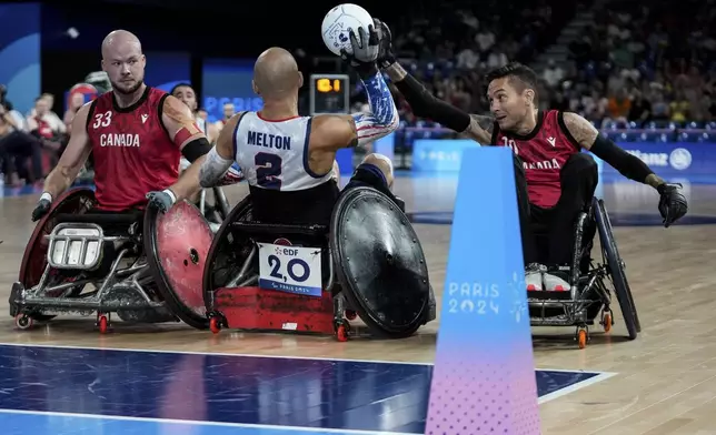 Zachary Madell of Canada, left, Chuck Melton of the United States, center, and Trevor Hirschfield of Canada challenge for the ball during the 2024 Paralympics Wheelchair Rugby match United States against Canada at the Champs Mars Arena Thursday, Aug. 29, 2024, in Paris, France. (AP Photo/Michel Euler)