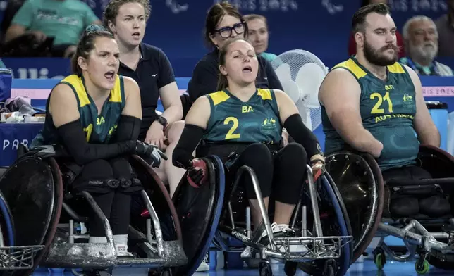 Australians Ella Sabljak, left, Emilie Miller, center, and Josh Nicholson watch the game from the sideline during the 2024 Paralympics Wheelchair Rugby match Australia against Great Britain, at the Champs Mars Arena, Thursday, Aug. 29, 2024, in Paris, France. (AP Photo/Michel Euler)