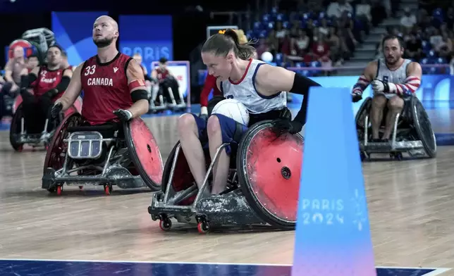 Sarah Adam of the United States makes a try as Zachary Madell of Canada look on during the 2024 Paralympics Wheelchair Rugby match United States against Canada at the Champs Mars Arena Thursday, Aug. 29, 2024, in Paris, France. (AP Photo/Michel Euler)