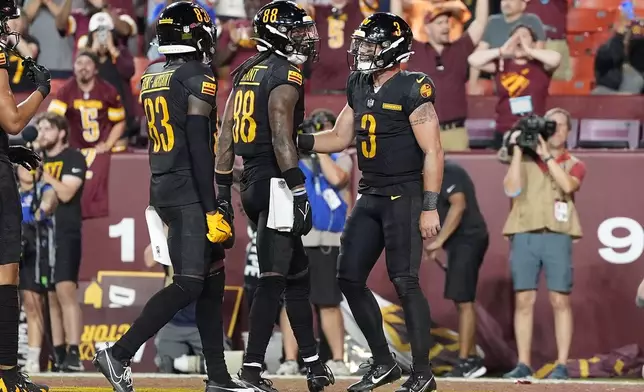 Washington Commanders wide receiver Martavis Bryant, middle, celebrates with wide receiver Marcus Rosemy-Jacksaint (83) and quarterback Trace McSorley (3) after scoring against the New England Patriots during the second half of a preseason NFL football game, Sunday, Aug. 25, 2024, in Landover, Md. (AP Photo/George Walker IV)