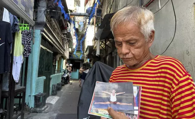 Rodrigo Frisco, 74-year-old grandfather of Filipino gymnast Carlo Yulo, who won two gold medals in the Paris Olympics, holds photos of his grandson on Tuesday, Aug. 13, 2024, in a neighborhood in Manila, Phillippines, where Yulo grew up. (AP Photo/Joeal Calupitan)