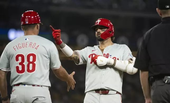 Philadelphia Phillies' Nick Castellanos, right, gestures after hitting an RBI single during the sixth inning of a baseball game against the Los Angeles Dodgers in Los Angeles, Tuesday, Aug. 6, 2024. (AP Photo/Kyusung Gong)