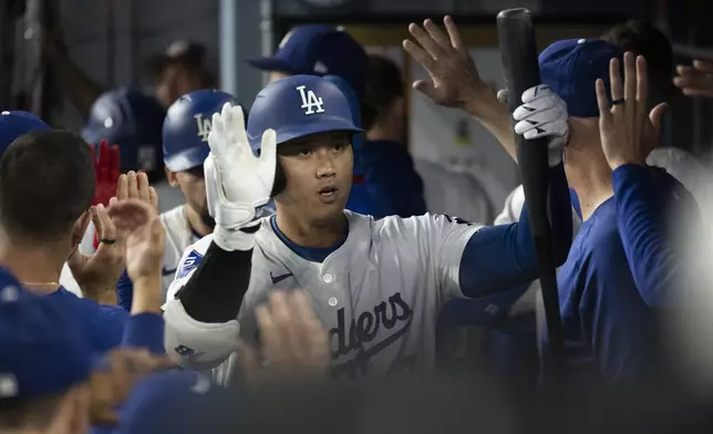 Los Angeles Dodgers' Shohei Ohtani celebrates in the dugout after scoring during the third inning of a baseball game against the Philadelphia Phillies in Los Angeles, Monday, Aug. 5, 2024. (AP Photo/Kyusung Gong)