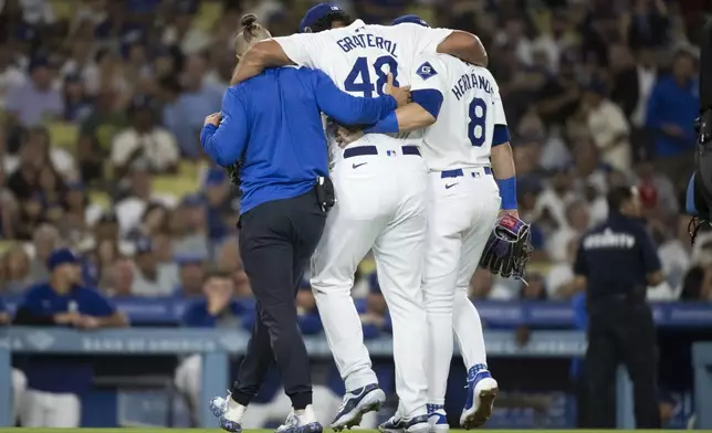 Los Angeles Dodgers relief pitcher Brusdar Graterol (48) is helped getting out of a baseball game against the Philadelphia Phillies due to an apparent injury in Los Angeles, Tuesday, Aug. 6, 2024. (AP Photo/Kyusung Gong)