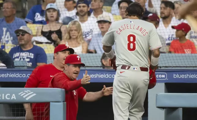 Philadelphia Phillies manager Rob Thompson, left, greets Nick Castellanos after he scored on an RBI single by Bryson Stott during the second inning of a baseball game against the Los Angeles Dodgers in Los Angeles, Monday, Aug. 5, 2024. (AP Photo/Kyusung Gong)