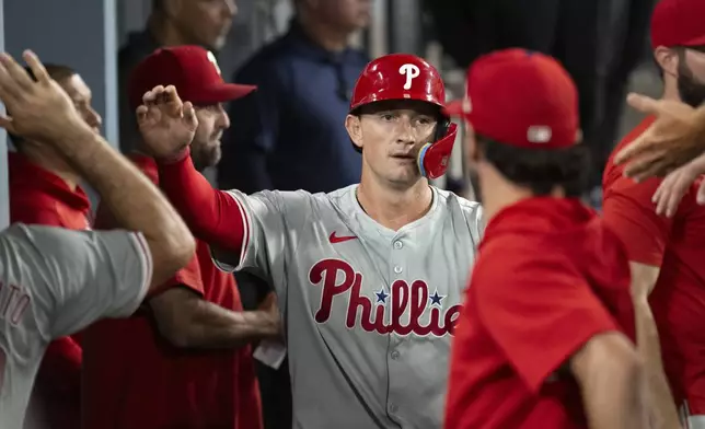 Philadelphia Phillies' Austin Hays celebrates in the dugout after scoring a run on an RBI single by Kyle Schwarber during the fifth inning of a baseball game against the Los Angeles Dodgers in Los Angeles, Tuesday, Aug. 6, 2024. (AP Photo/Kyusung Gong)