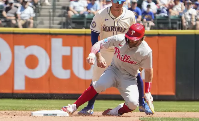 Philadelphia Phillies Bryce Harper slides into second base against Seattle Mariners shortstop Dylan Moore during the fourth inning of a baseball game, Sunday, Aug. 4, 2024, in Seattle. (AP Photo/Liv Lyons)